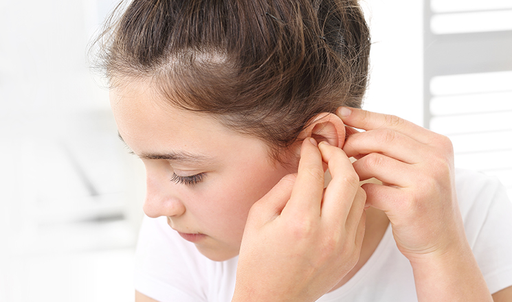 child putting on a hearing aid