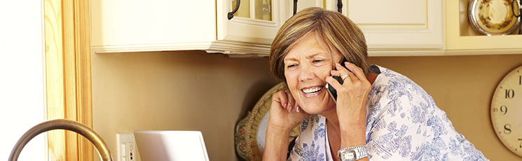 Middle-aged woman in a kitchen making a phone call about her lost hearing aid